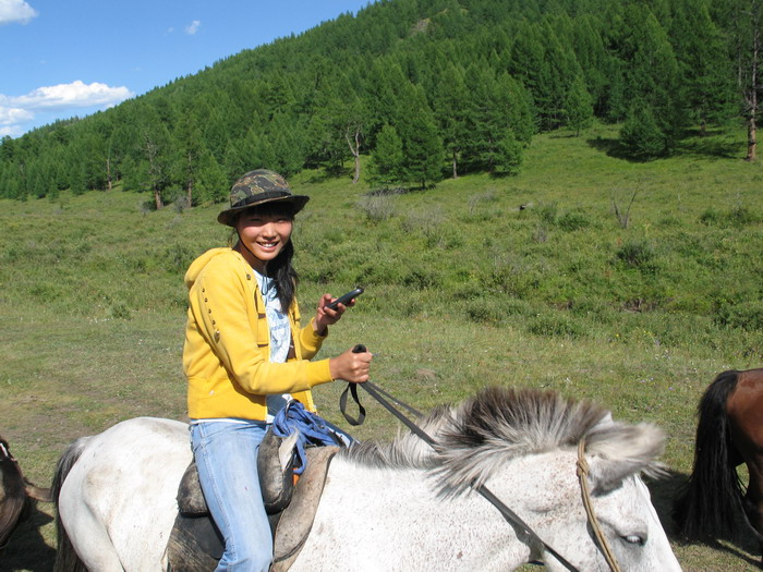 Sina, a modern Mongolian woman, on horseback with her mobile phone.