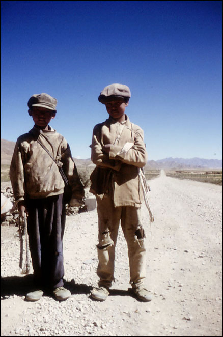 These nomad kids use their sling shots (the thing that looks like rope that each are holding) on help herd their sheep. Shigatse, Tibet.