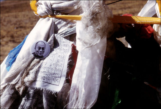 A button with an image of the Dalai Lama, along with many prayer flags mark the top of a pass. The Chinese government has stated that all pictures of the Dalai are illegal inside of Tibet. Lhatze, Tibet.